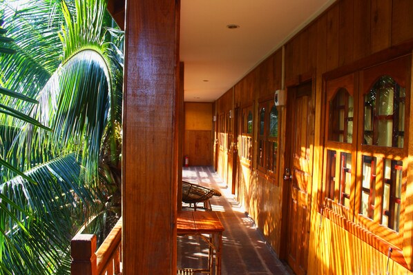 Un pasillo con paredes de madera, un banco y una palmera.