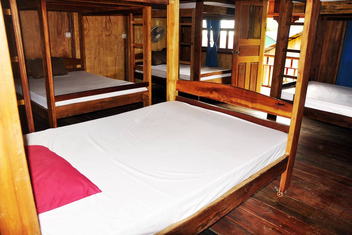 A wooden bunk bed room with a single bed and a bunk above.