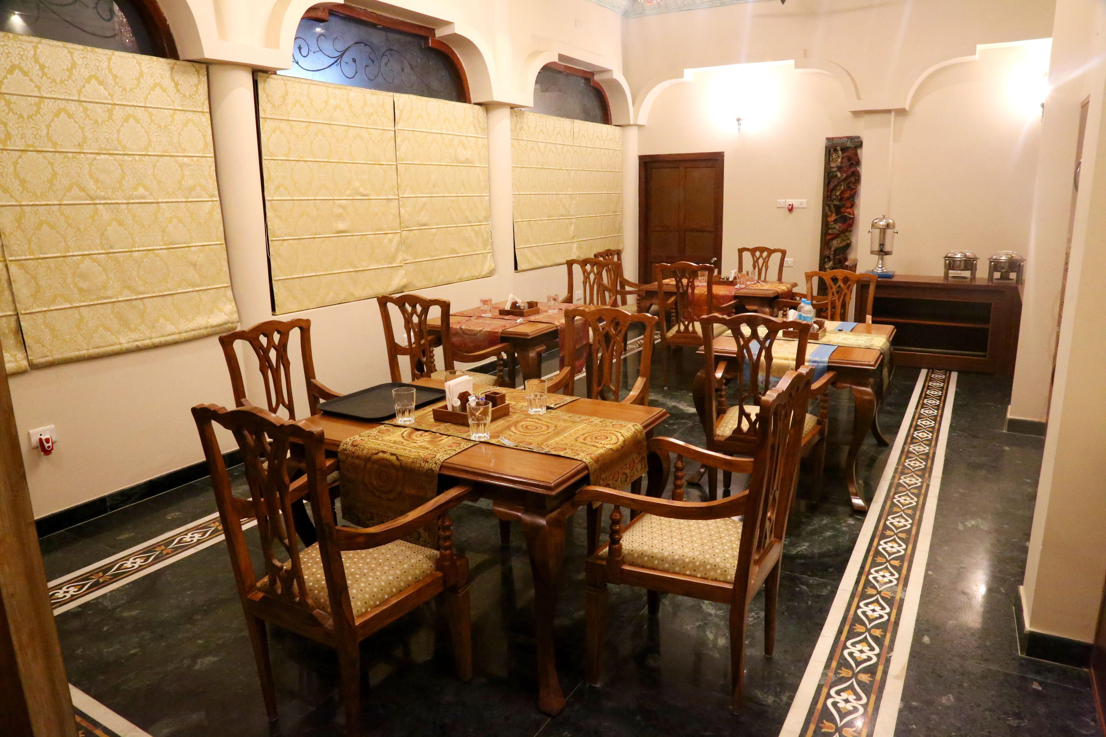 A dining area with wooden tables and chairs, patterned wall coverings, and a decorative floor design.
