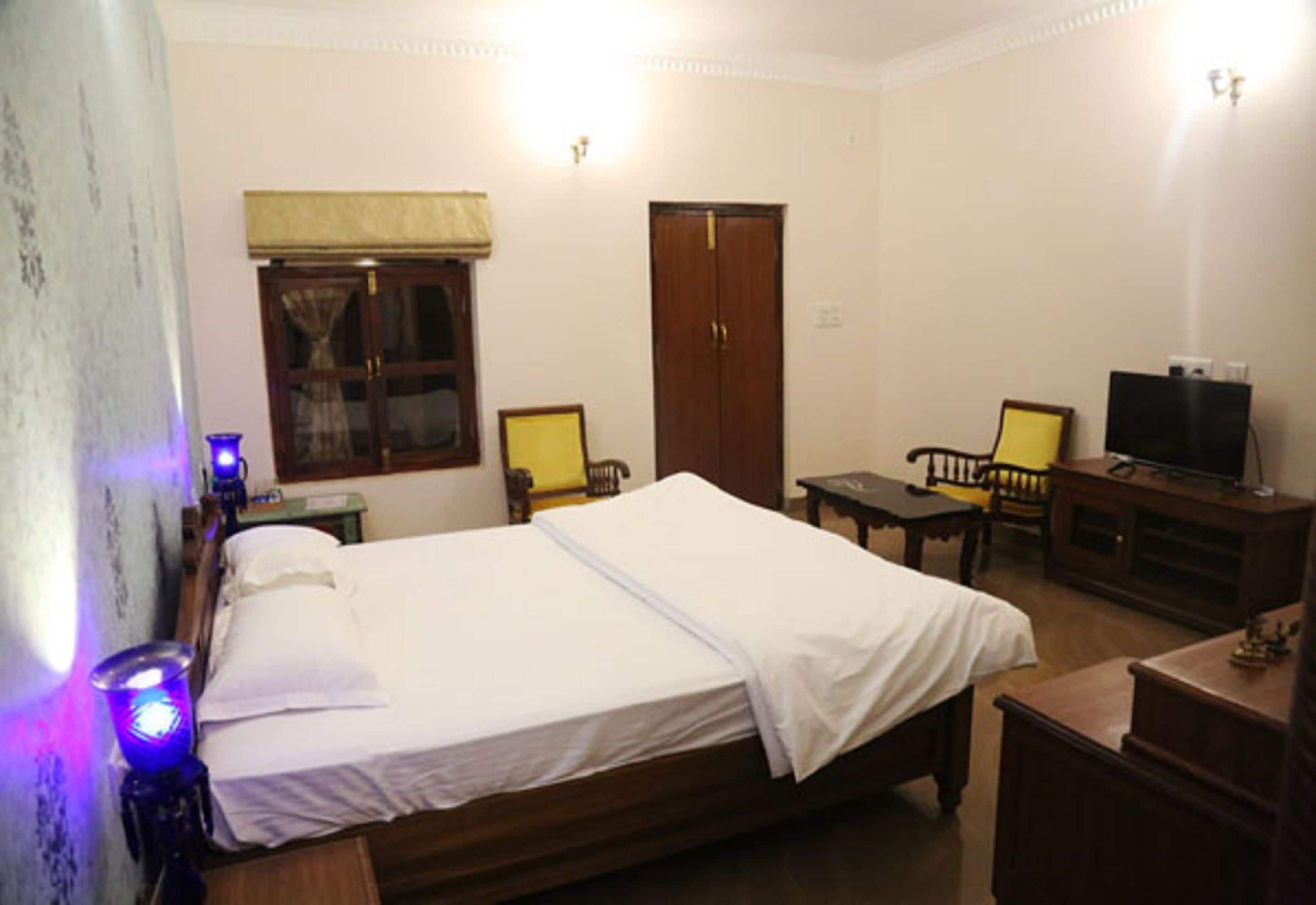 A room with a bed, a desk, a chair, a television, and a wardrobe.