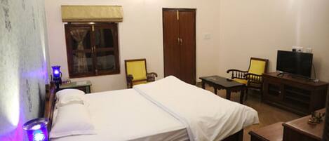 A room with a bed, a desk, a chair, a television, and a wardrobe.