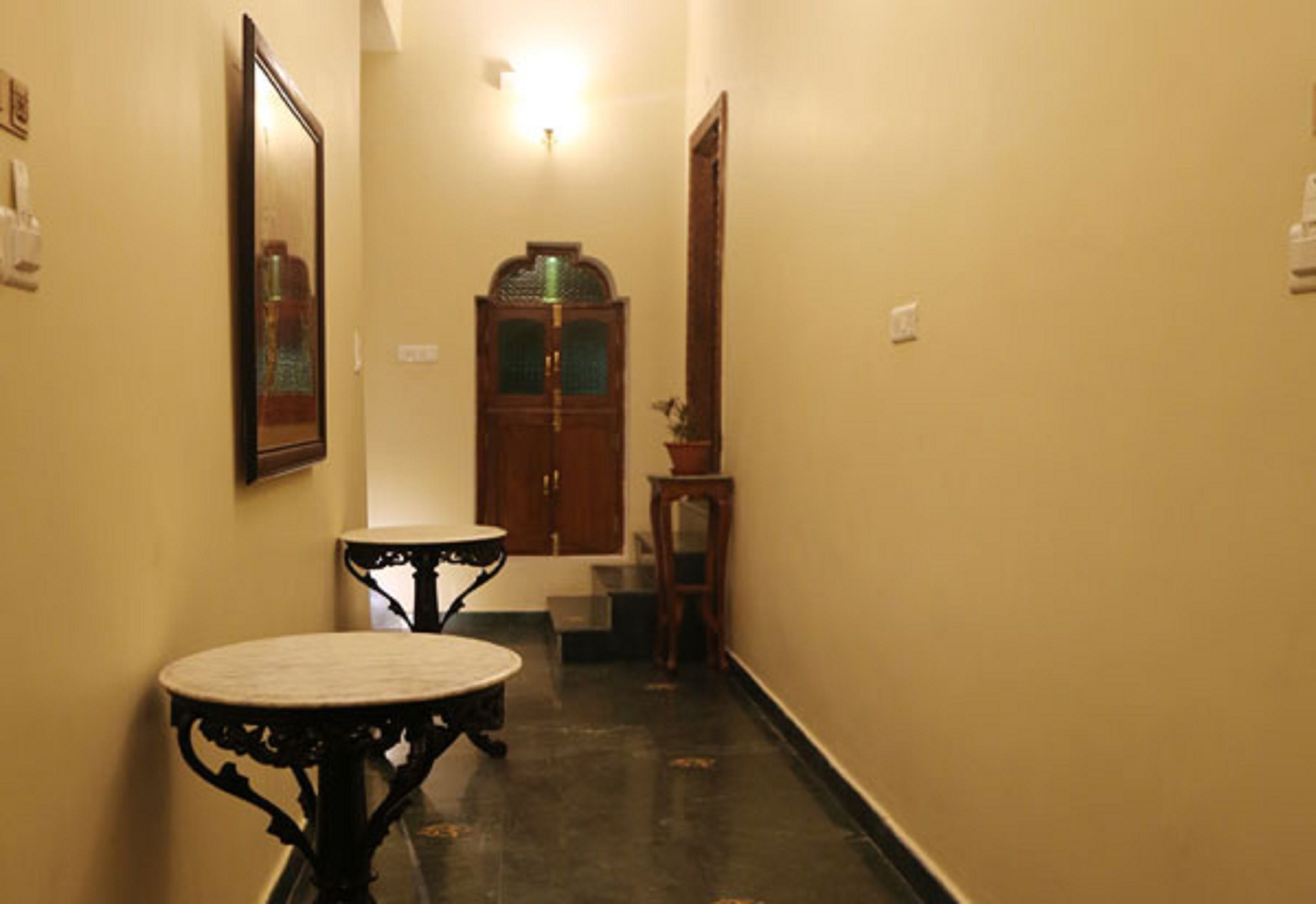 A narrow hallway with a round table and chairs, a wooden cabinet, and a small side table.