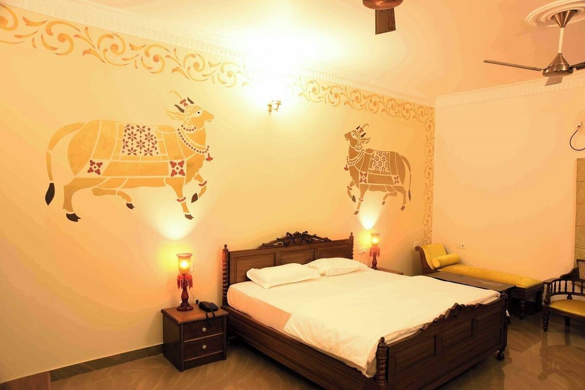 A bedroom with a wooden bed, two wall-mounted lamps, and decorative wall art of a cow.