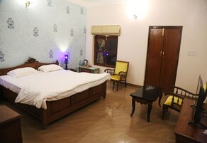 A bedroom with a wooden bed, a small table, a chair, and a wardrobe.