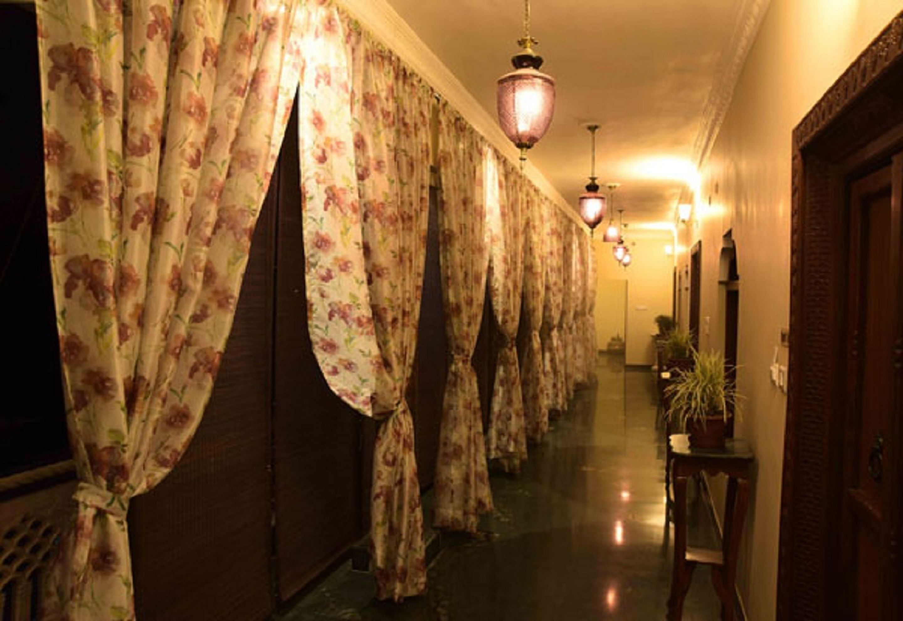 Un pasillo con cortinas florales, puertas de madera y lámparas colgantes.