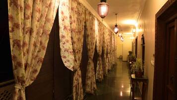 Un pasillo con cortinas florales, puertas de madera y lámparas colgantes.