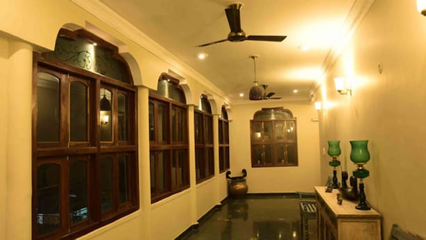 A hallway with wooden cabinets, a ceiling fan, and wall sconces. - Vijaigarh kothi (Varanasi)