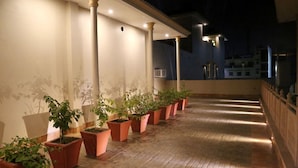 A covered outdoor corridor with terracotta planters and a tiled floor. - Vijaigarh kothi (Varanasi)