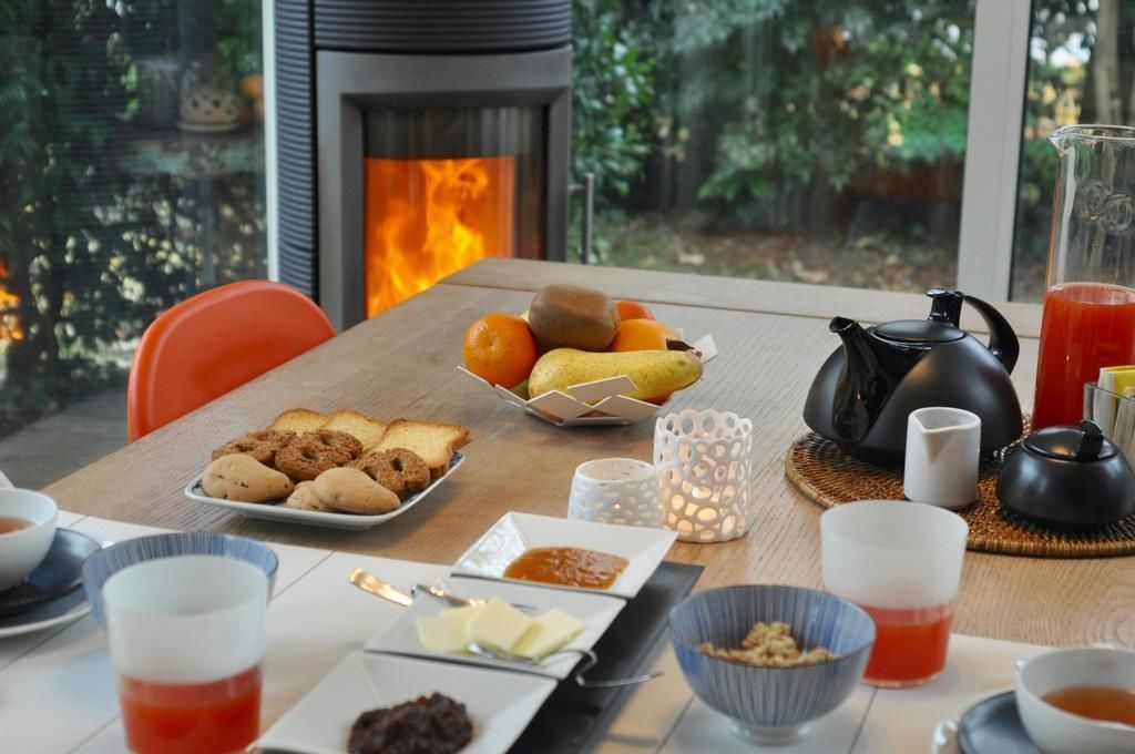 A breakfast table with fruits, pastries, tea, and a teapot.