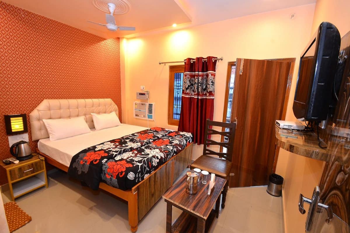 A bedroom with a bed, bedside table, and a small table with a kettle and cups.
