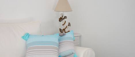 A white sofa with striped pillows and a hanging lamp.