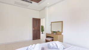 A hotel room with a bed, a wooden desk, a mirror, and a door. - Karon Hill Villa (Karon)