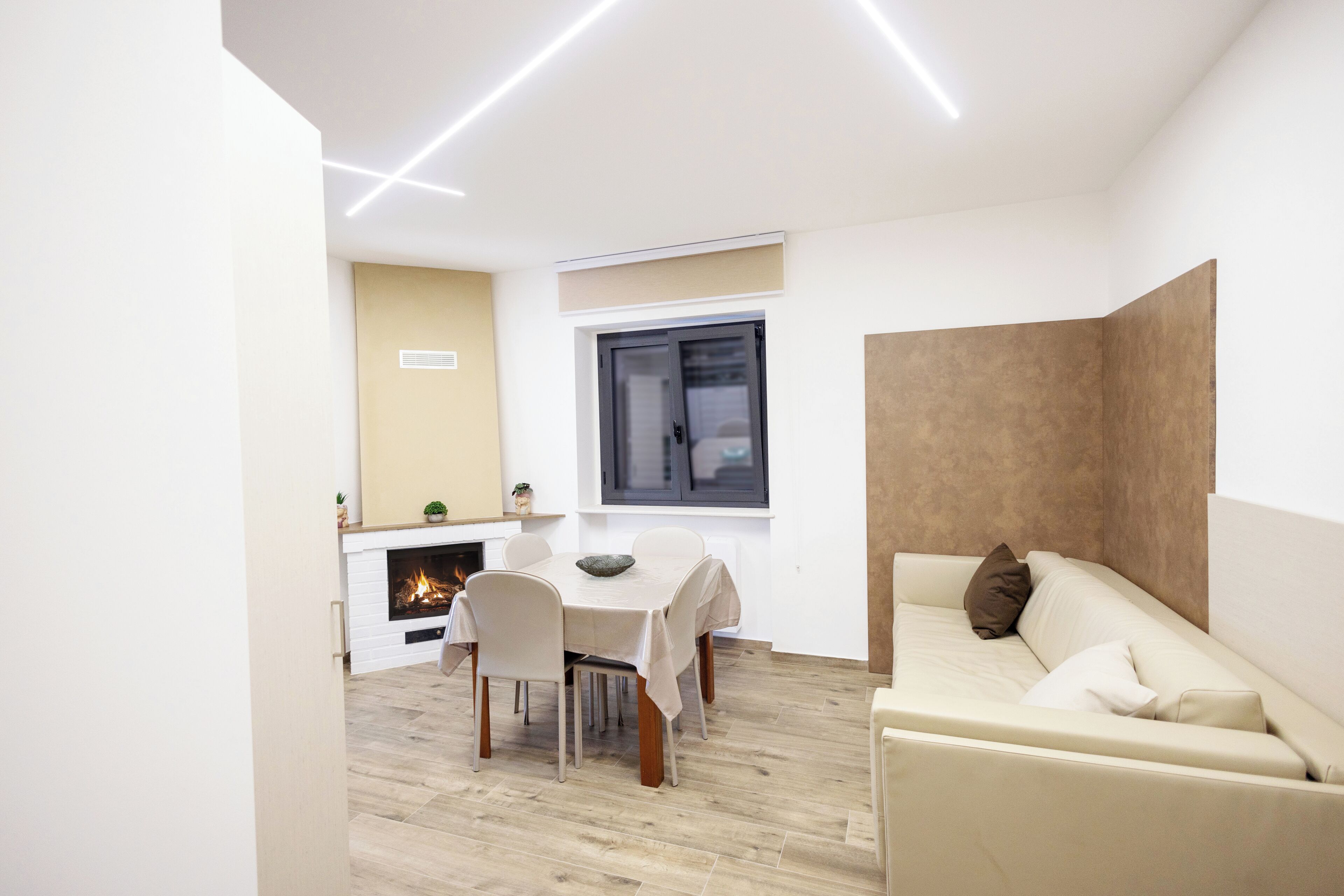 Una sala de estar moderna con chimenea, un comedor con mesa y sillas, y un sofá con cojines.