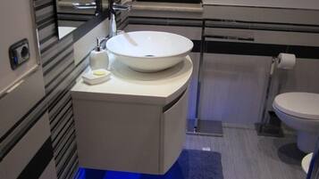 Ein modernes Badezimmer mit einem weißen Waschbecken, einer Toilette und einem Spiegel.