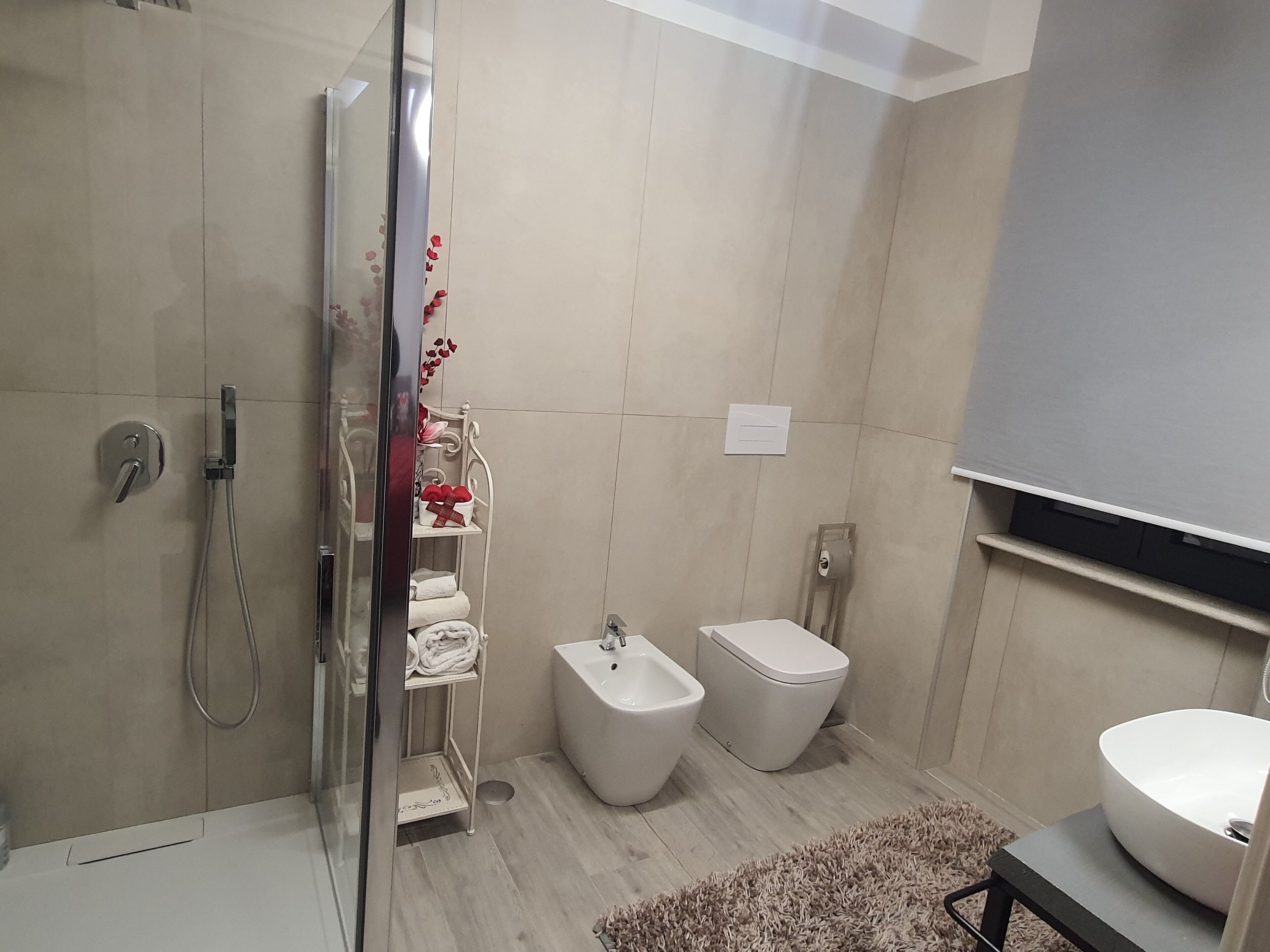 A modern bathroom with a glass shower enclosure, a bidet, a toilet, and a sink.