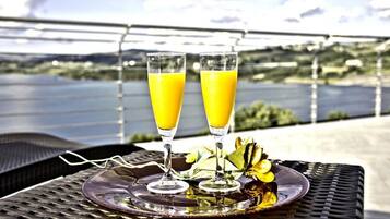 Zwei Gläser Orangensaft auf einem Tablett mit einer Zierblume, platziert auf einem Tisch mit einer Metallgitteroberfläche.