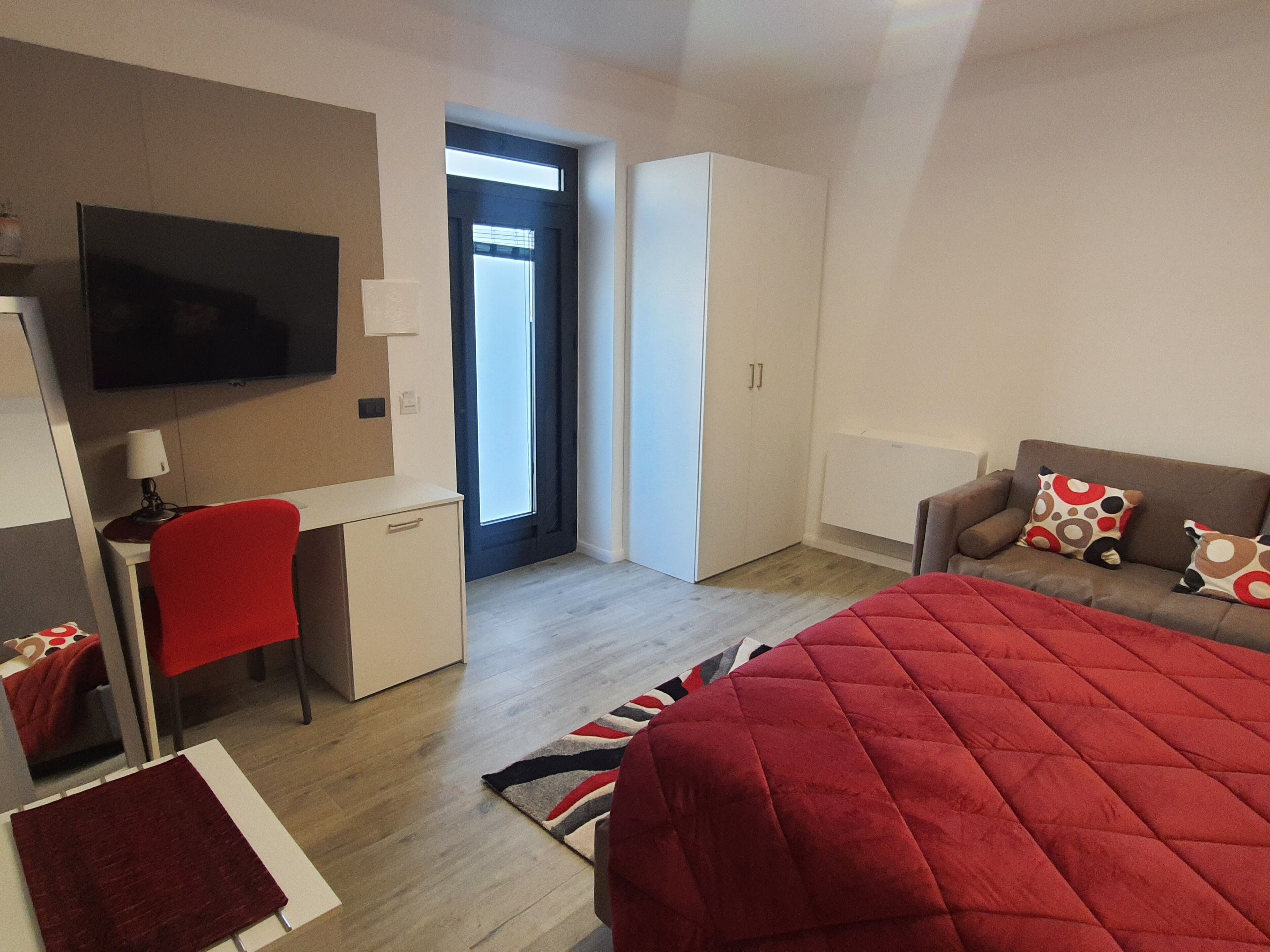 Ein modernes Hotelzimmer mit Bett, Schreibtisch, Stuhl, Fernseher und Kleiderschrank.