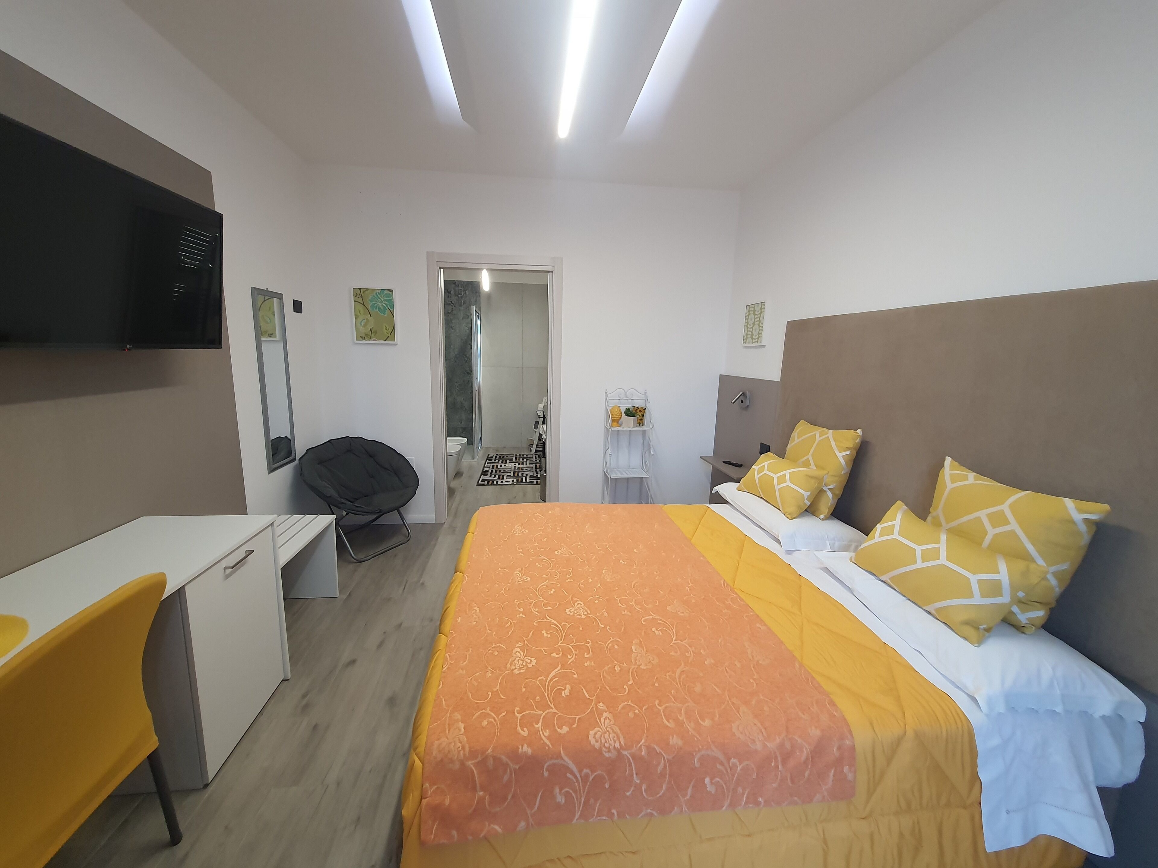 Une chambre d’hôtel moderne équipée d’un lit, d’un bureau, d’une chaise et d’un espace douche.