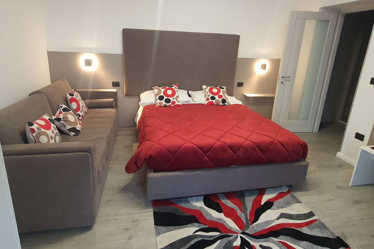 Ein Schlafzimmer mit einem Bett, einem Sofa und einem gemusterten Teppich.