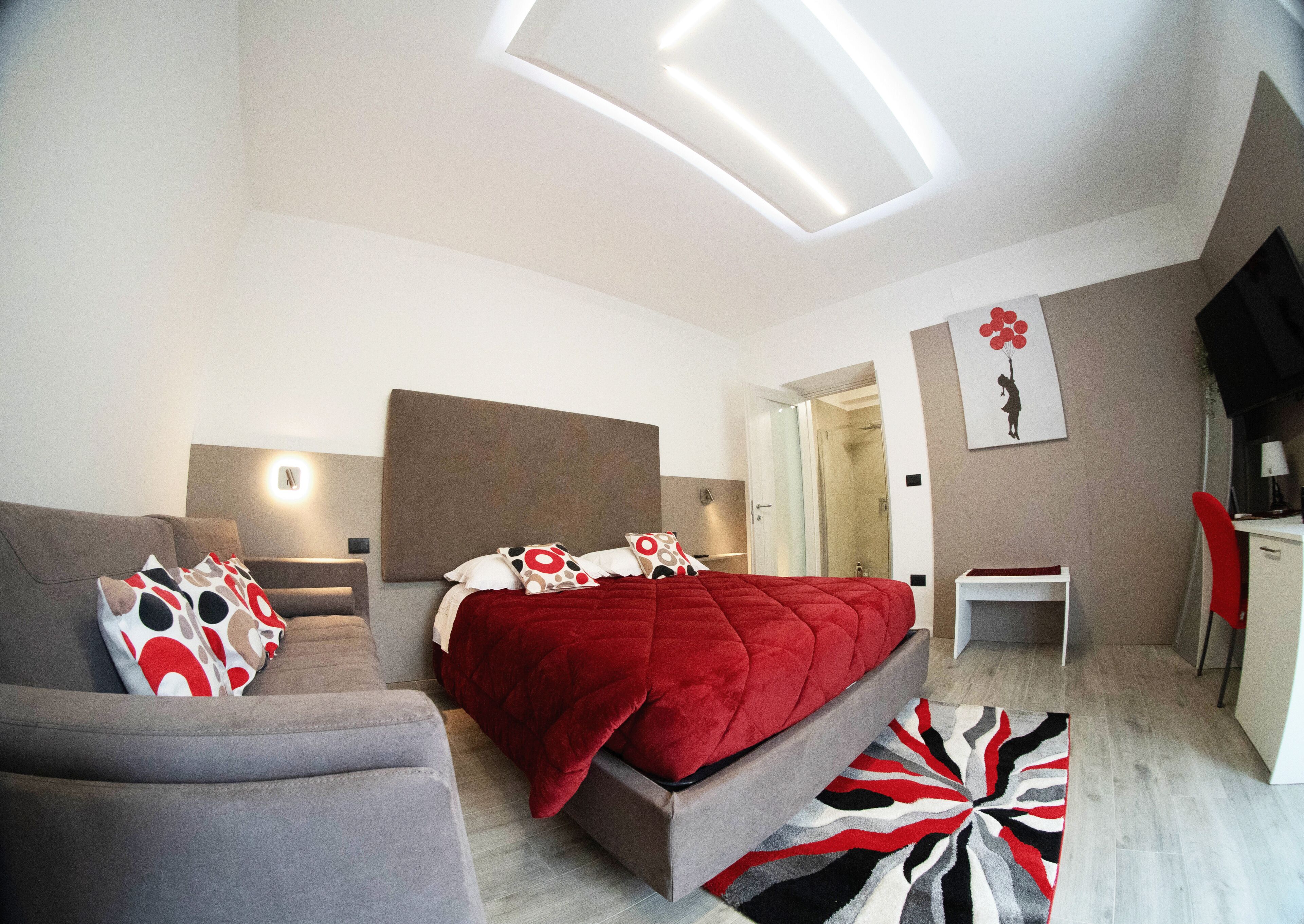 Quarto moderno com cama, sofá, escrivaninha e área de chuveiro.