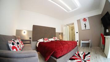 Quarto moderno com cama, sofá, escrivaninha e área de chuveiro.