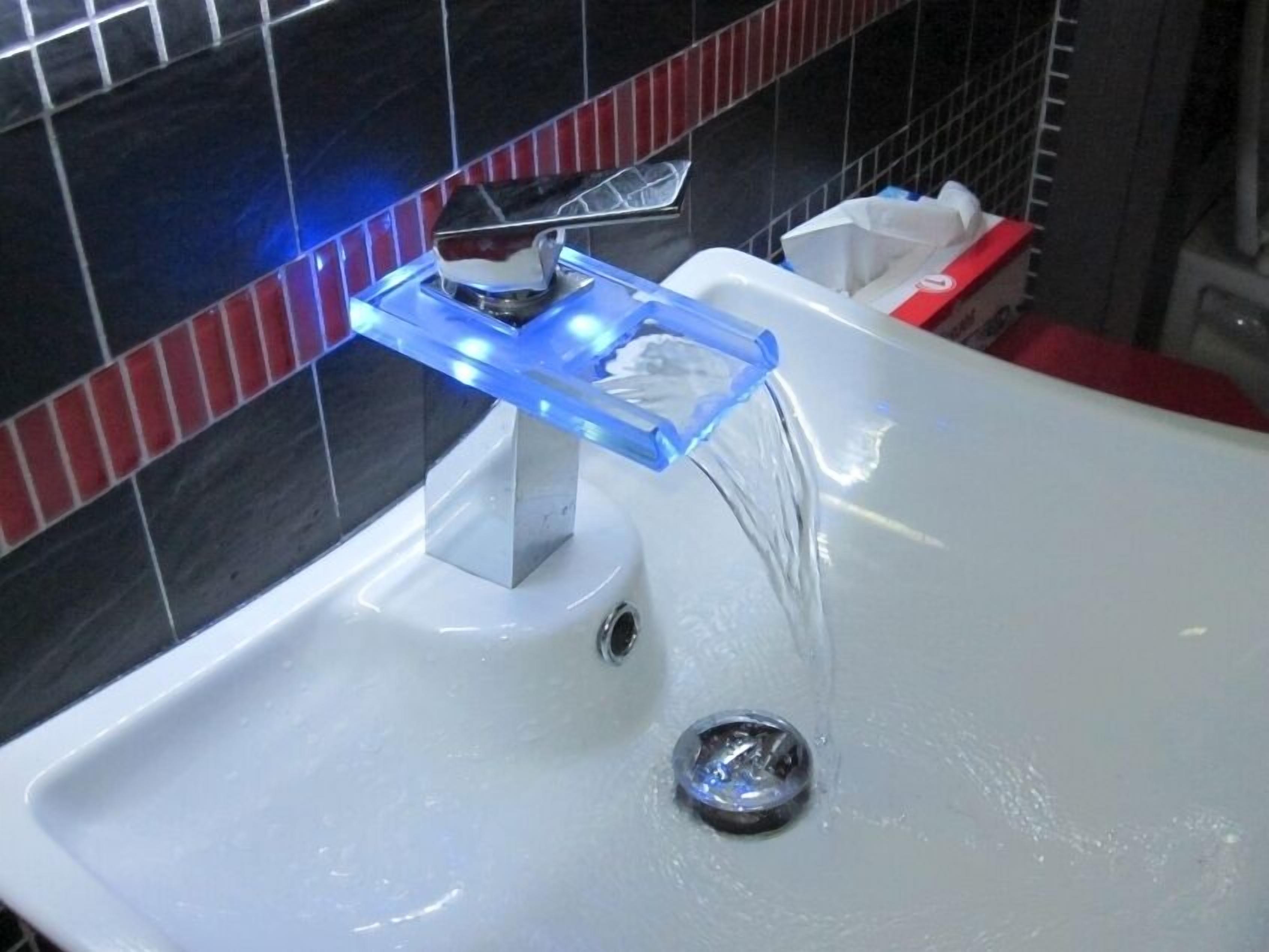 Ein Waschbecken mit modernem Wasserhahn und einer blauen Seifenschale.