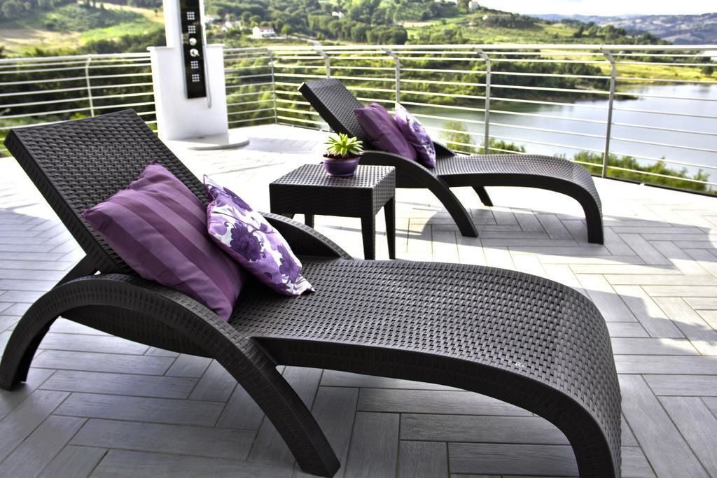 Een balkon met twee loungestoelen en een klein tafeltje, met uitzicht op een meer en groen.