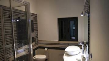 Een moderne badkamer met een douchecabine van glas, een witte wastafel en een toilet.