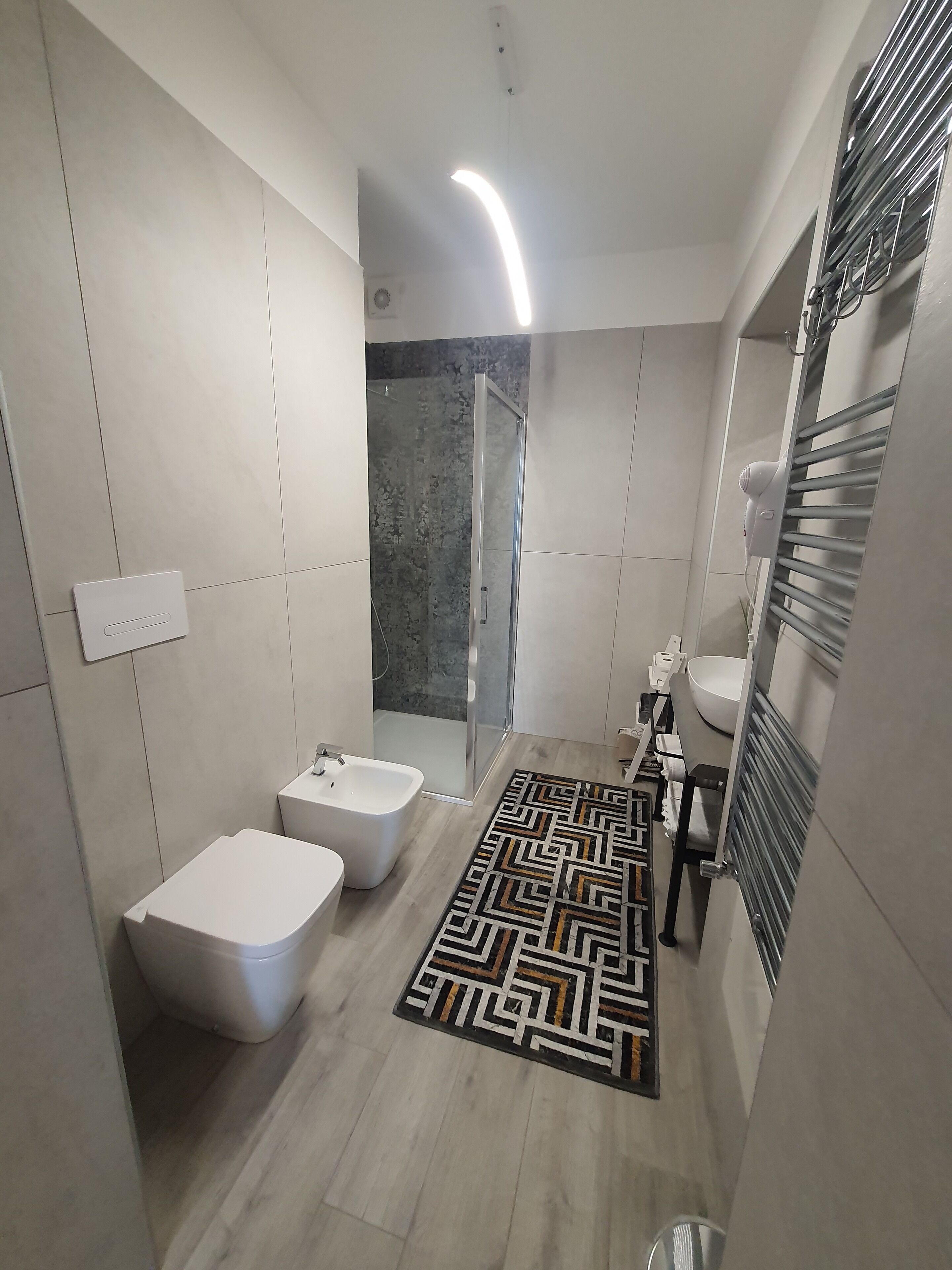 A modern bathroom with a bidet, a shower, and a vanity with a mirror.