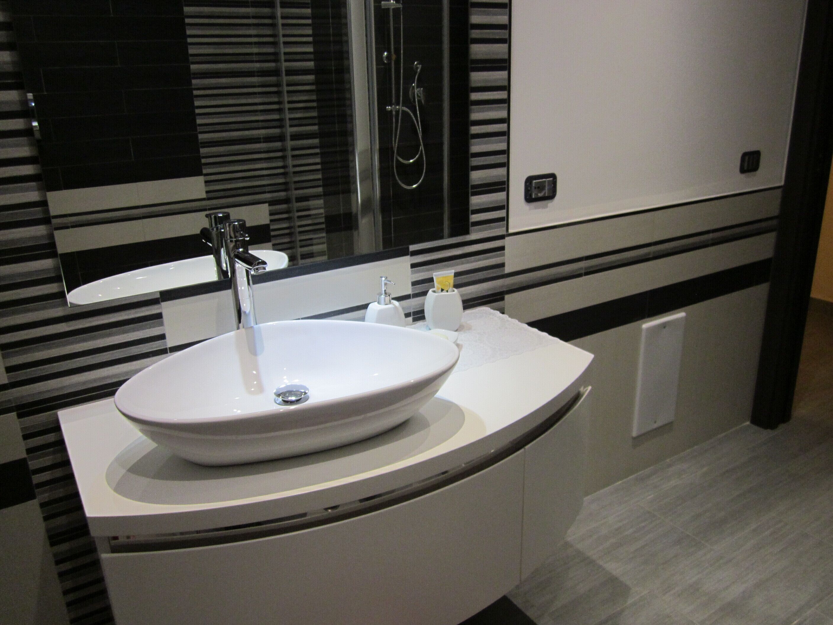 Un bagno moderno con un lavandino bianco grande, uno specchio e una doccia.