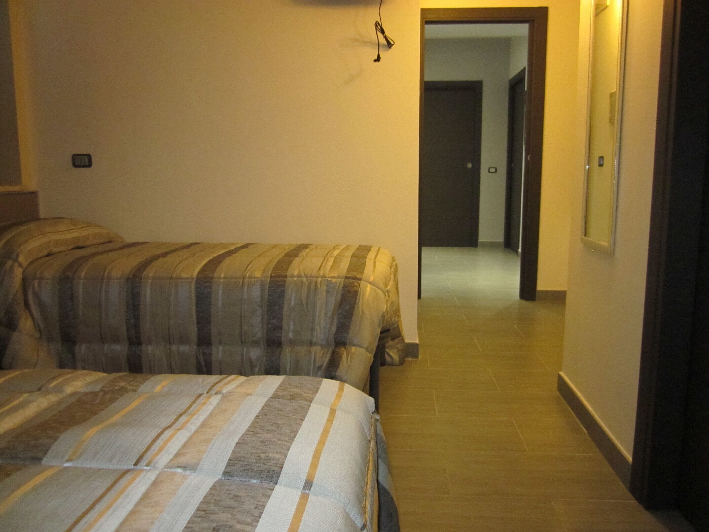 Ein Schlafzimmer mit zwei Betten, einem Flur und einer Tür zu einem weiteren Raum.