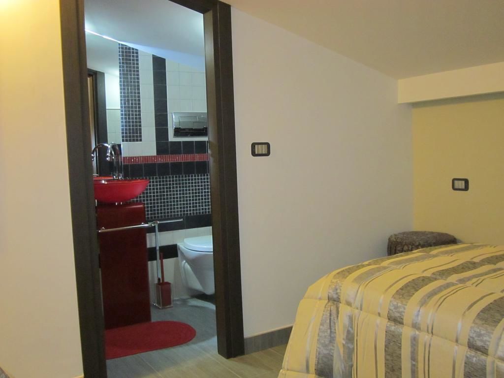 Een hotelkamer met een bed, een rode wastafel, een wit toilet en een spiegel.