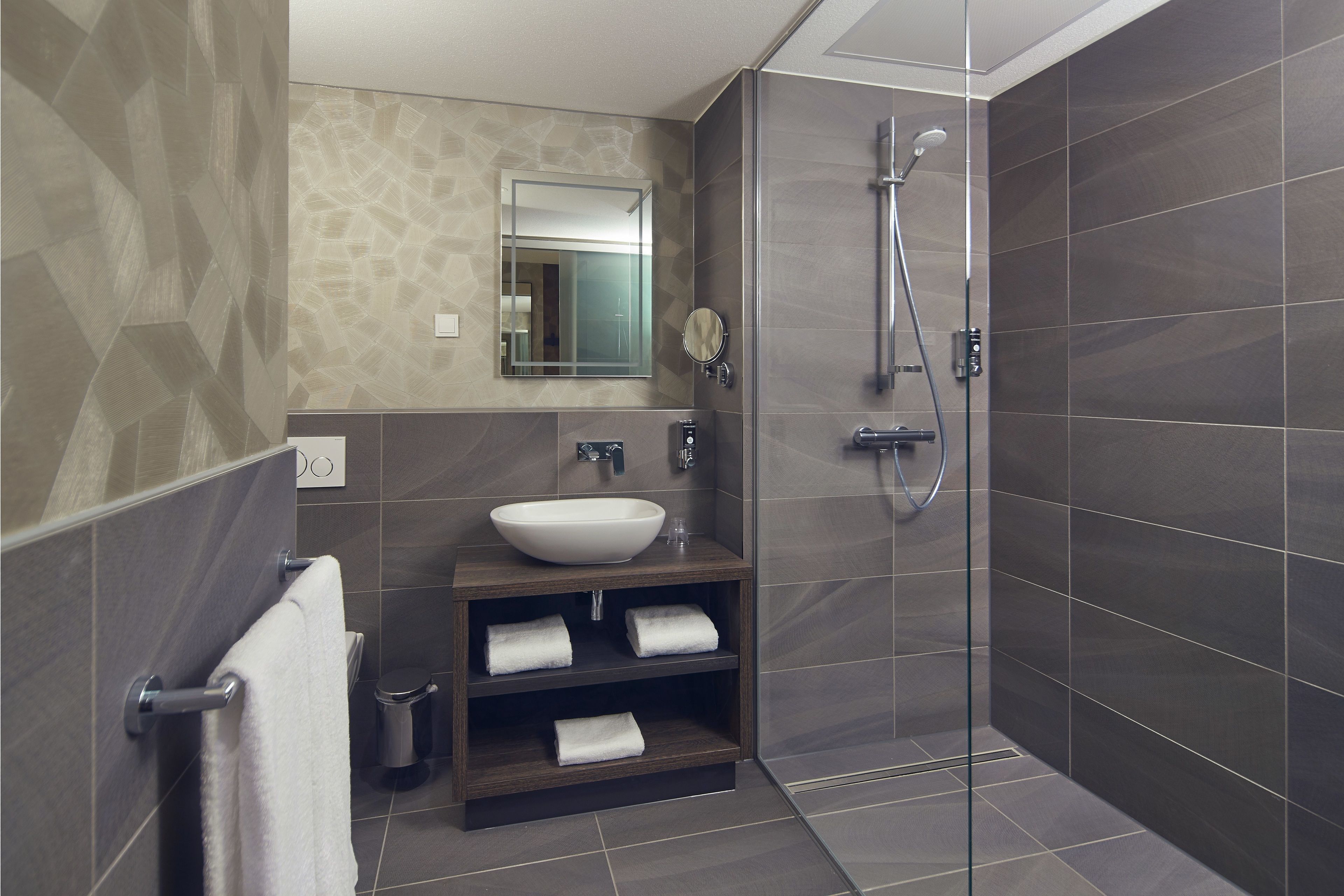 A modern bathroom with a large sink, mirror, and shower.
