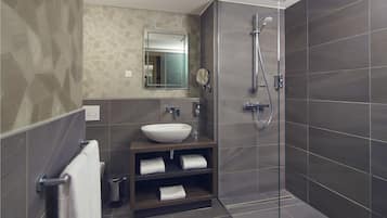 A modern bathroom with a large sink, mirror, and shower.