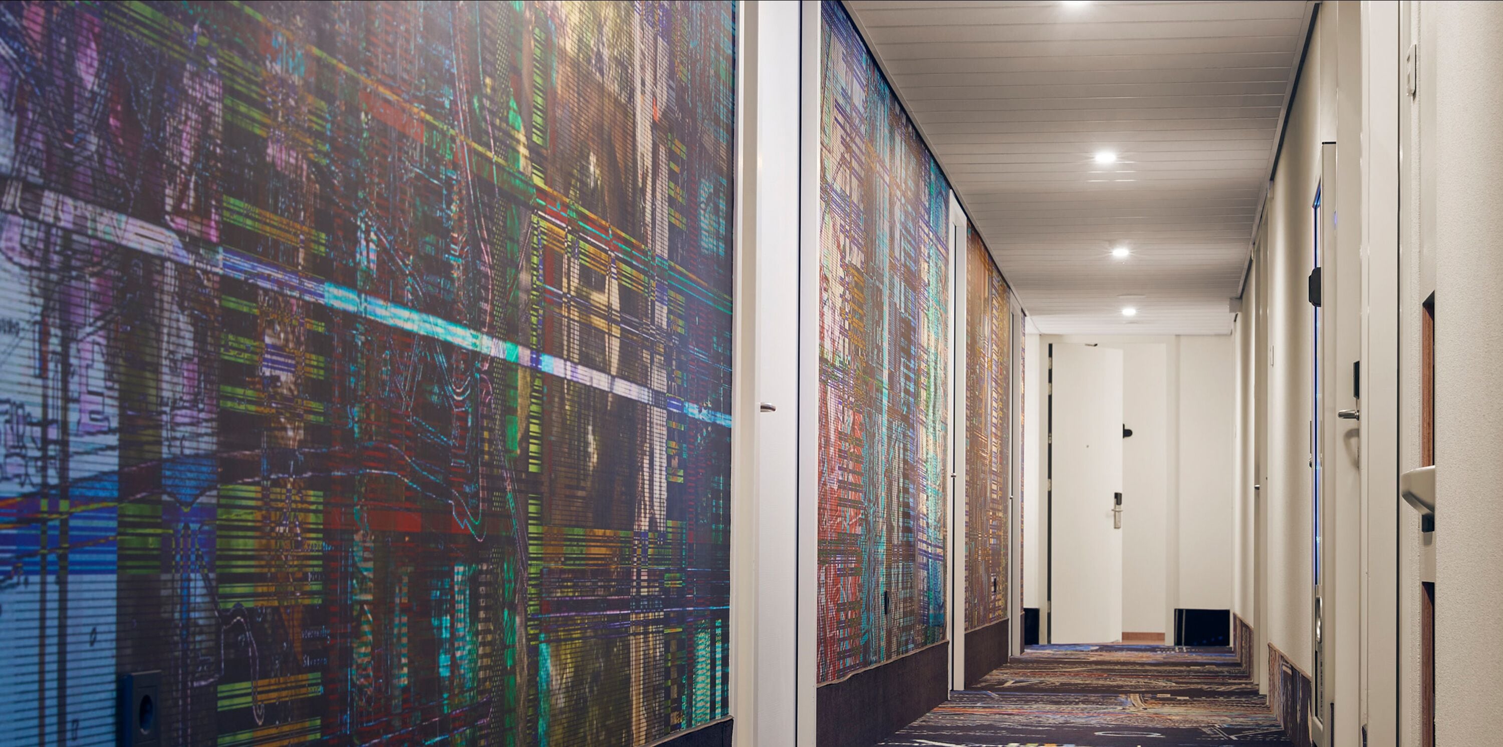 A hallway with a digital art installation on the walls, a carpeted floor, and a white ceiling.