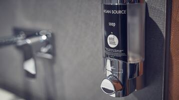 Un sèche-mains avec une étiquette indiquant « ARGAN SOURCE » et « SAPPHIRE », fixé au mur.
