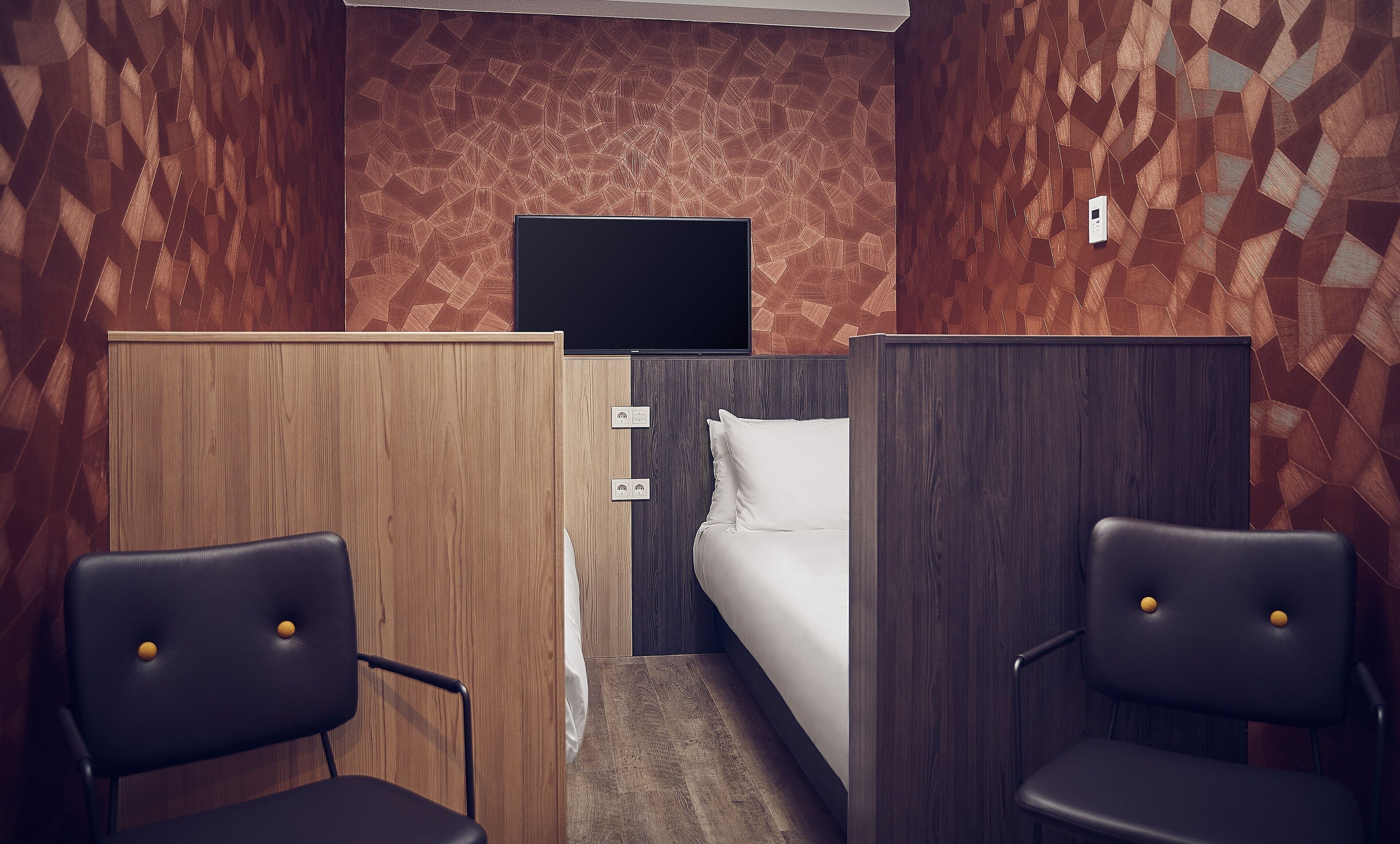 Een hotelkamer met een bed, een televisie en twee stoelen.