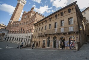 Un edificio histórico con una torre de reloj, ventanas en arco y una tienda que vende recuerdos.