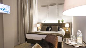 Une chambre d’hôtel comprenant un lit, une chaise, une table de chevet avec un plateau, et un téléviseur fixé au mur.