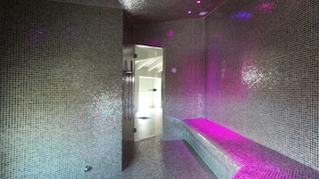 Experience the sleek bathroom with a mosaic tile design, curved bench, and modern ceiling grid.