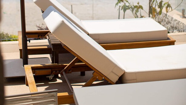 Eine Strandlounge mit Liegestühlen und Sonnenschirm, mit Blick aufs Meer.