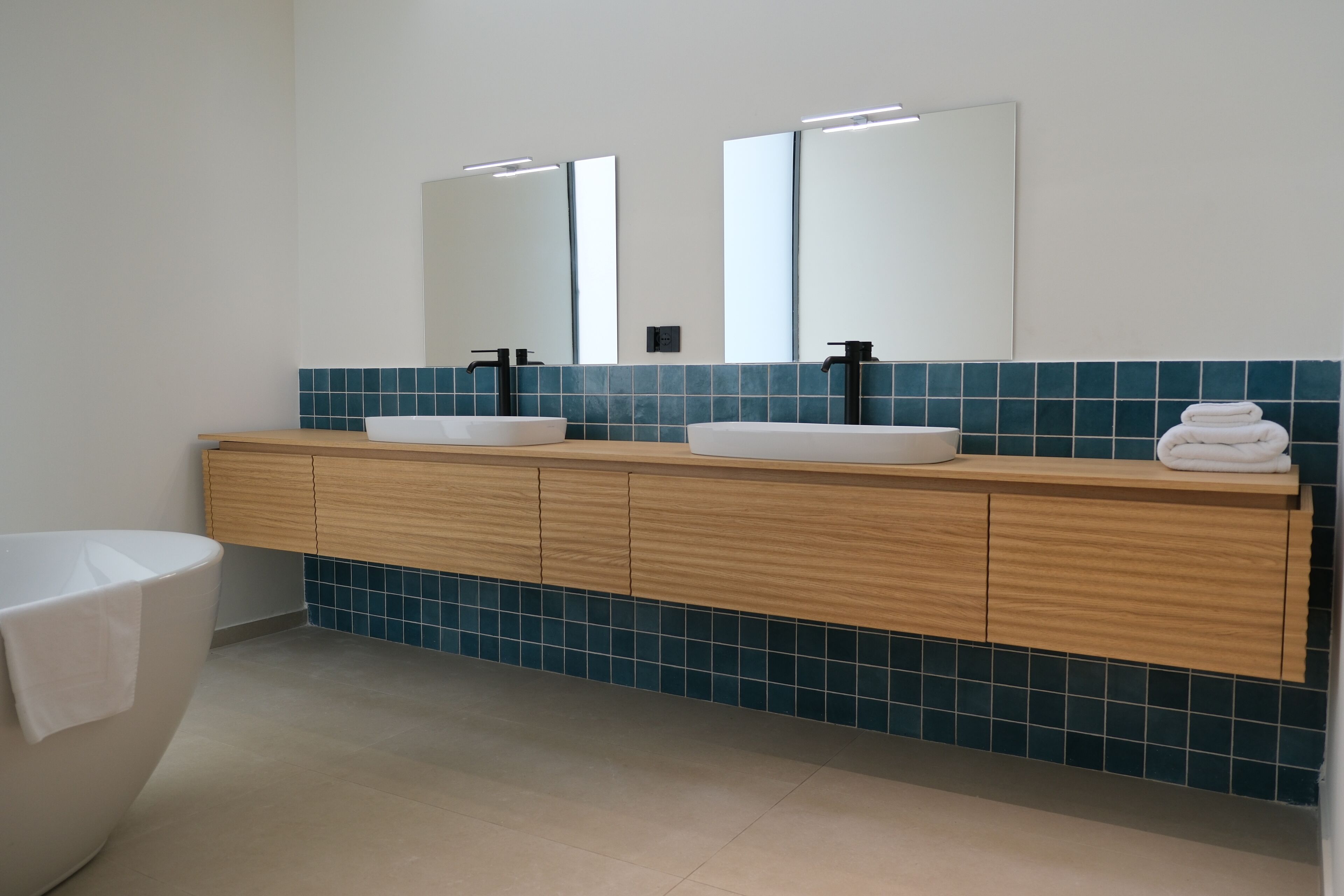 Une salle de bain moderne avec un meuble-lavabo en bois, deux vasques et un grand miroir.