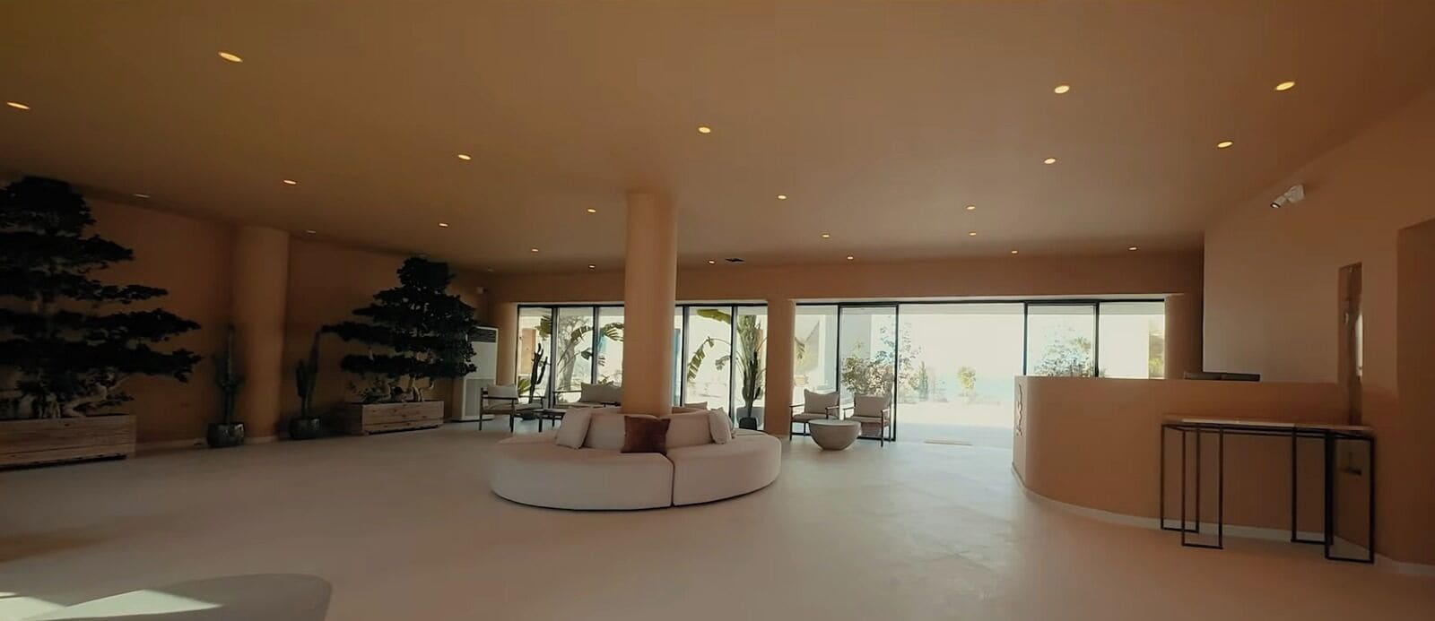 A spacious lobby with a large, round, white sofa, several chairs, and a tall column.