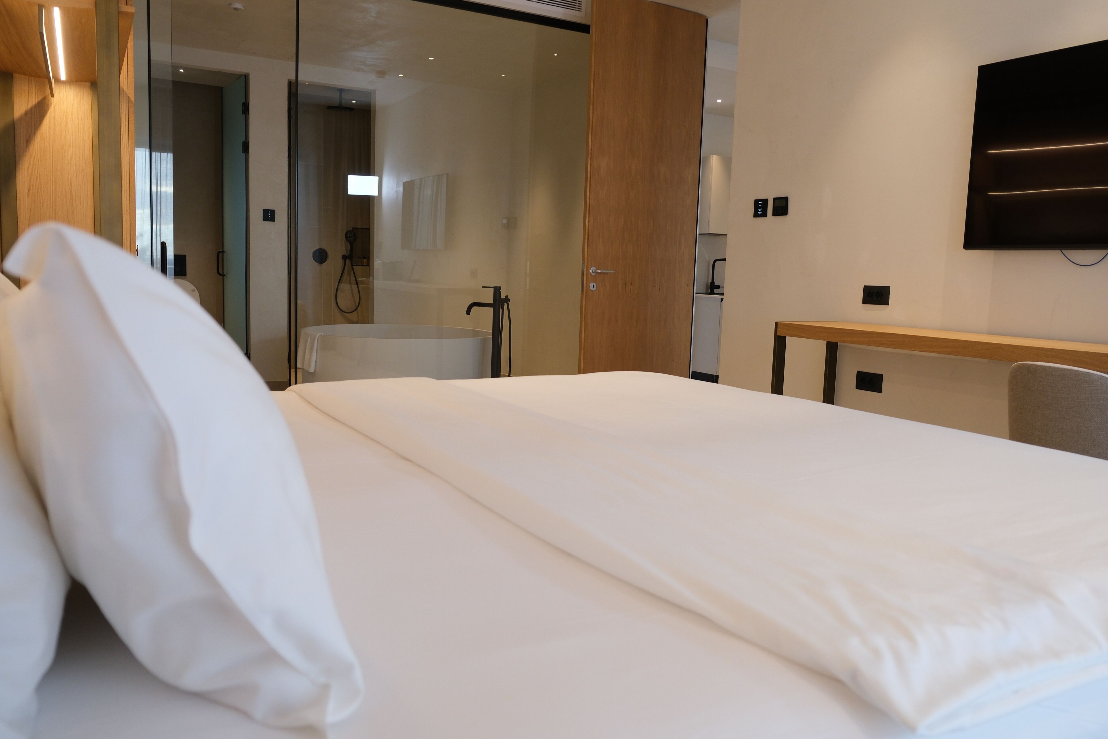 Une chambre d’hôtel avec un grand lit, un bureau en bois et un téléviseur fixé au mur.