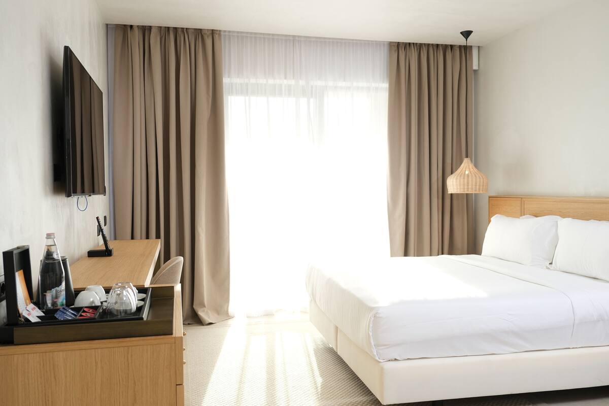 Een hotelkamer met een bed, bureau, televisie en raam met gordijnen.