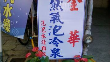 Uma placa com caracteres chineses, uma fonte de água e um banner com caracteres chineses.