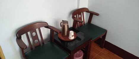 Un comedor con una mesa de madera y dos sillas, una cafetera y una taza sobre la mesa.