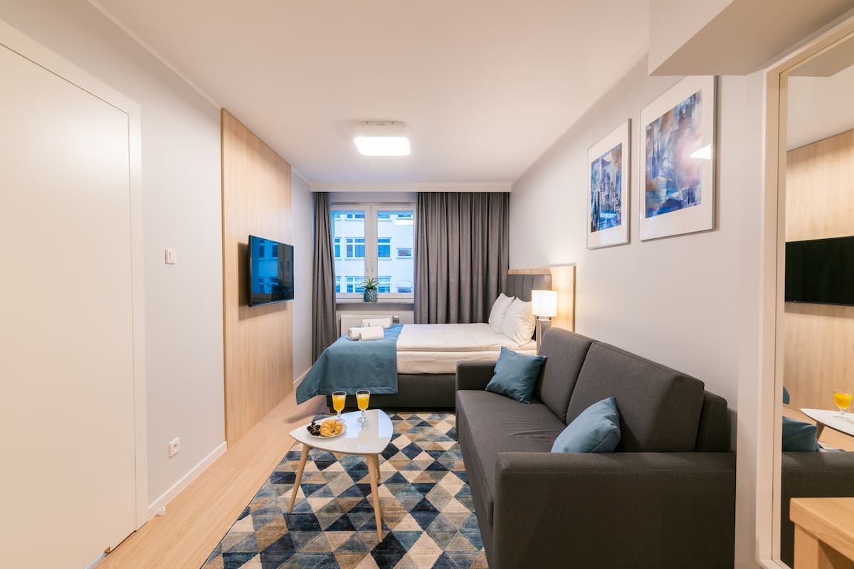 Une chambre d’hôtel moderne équipée d’un lit, d’un canapé, d’une télévision et d’un coin repas avec une table et des chaises.