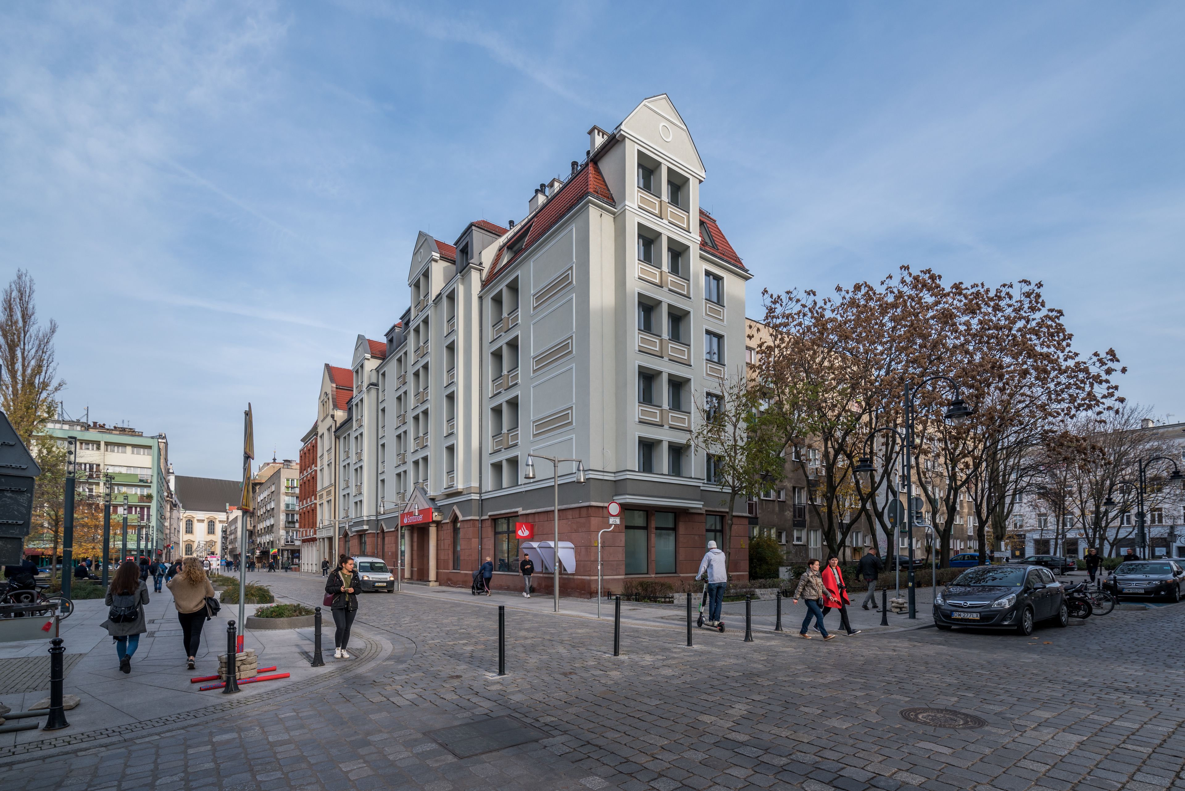 A multi-story building with a modern architectural design, featuring a prominent corner entrance and a red-tiled roof.