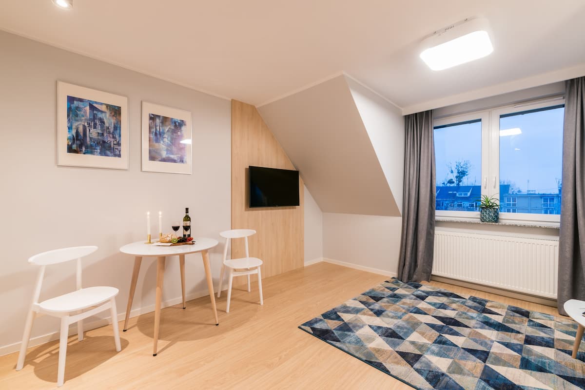 Une chambre moderne dotée d’un coin repas, d’un téléviseur fixé au mur et d’une grande fenêtre offrant une vue sur la ville.